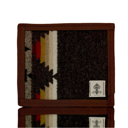 A rectangular Pendleton mat featuring a geometric pattern with upcycled fabric, predominantly in brown, black, and white colors, with a small brand tag displaying 'Wook Wear'.