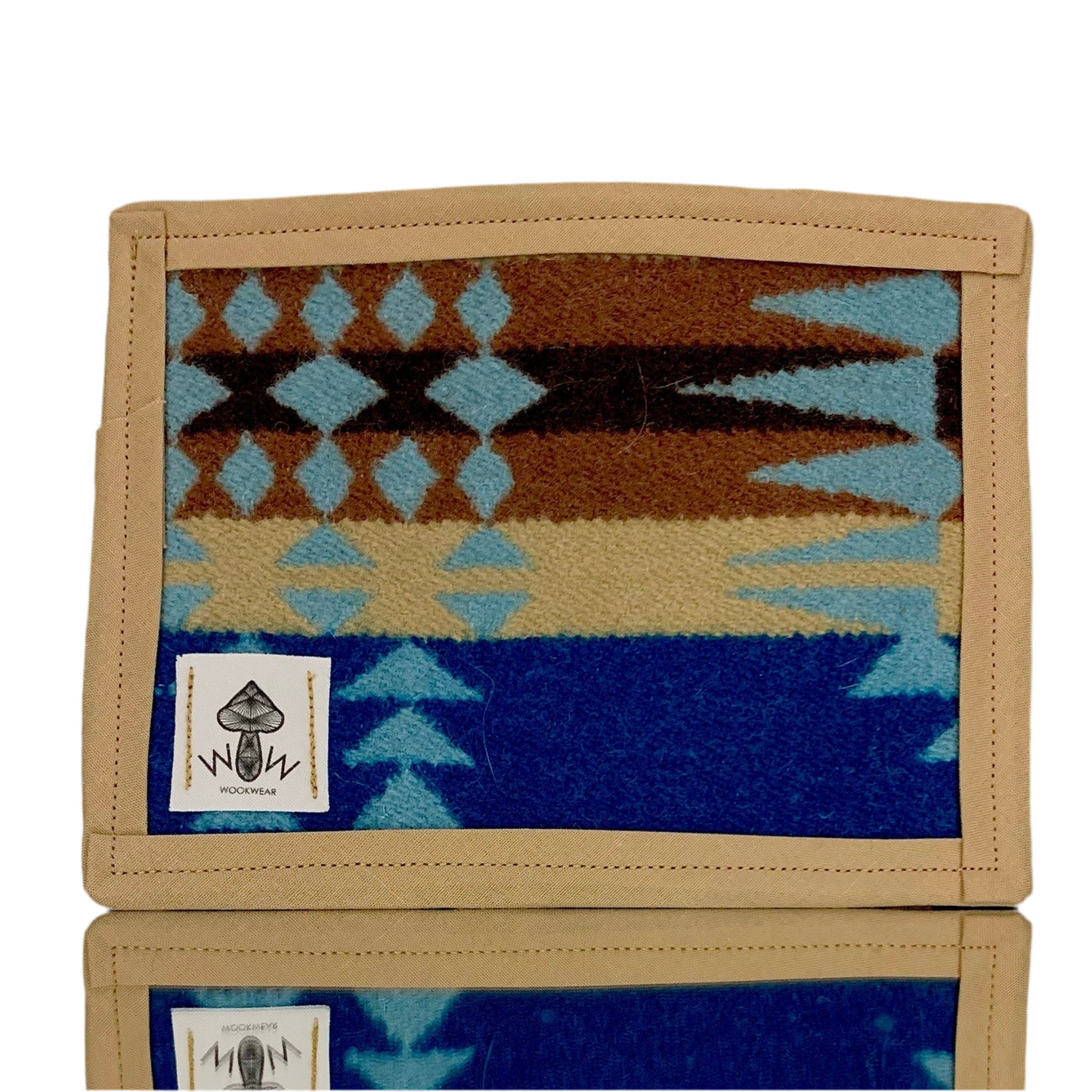 An upcycled fabric mat with geometric patterns and a label showing the brand name 'Wook Wear'.