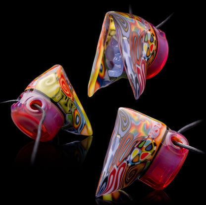 A colorful glass pipe shaped like a reaper with a scythe, featuring abstract designs and a removable dabber.