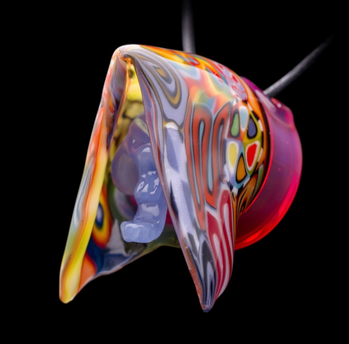 A colorful glass pipe shaped like a reaper with a scythe, featuring abstract designs and a removable dabber.