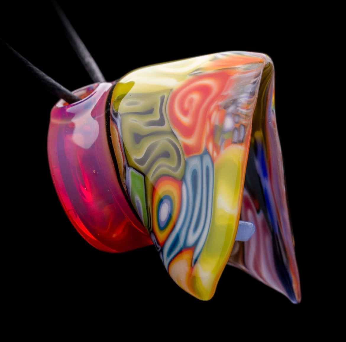 A colorful glass pipe shaped like a reaper with a scythe, featuring abstract designs and a removable dabber.