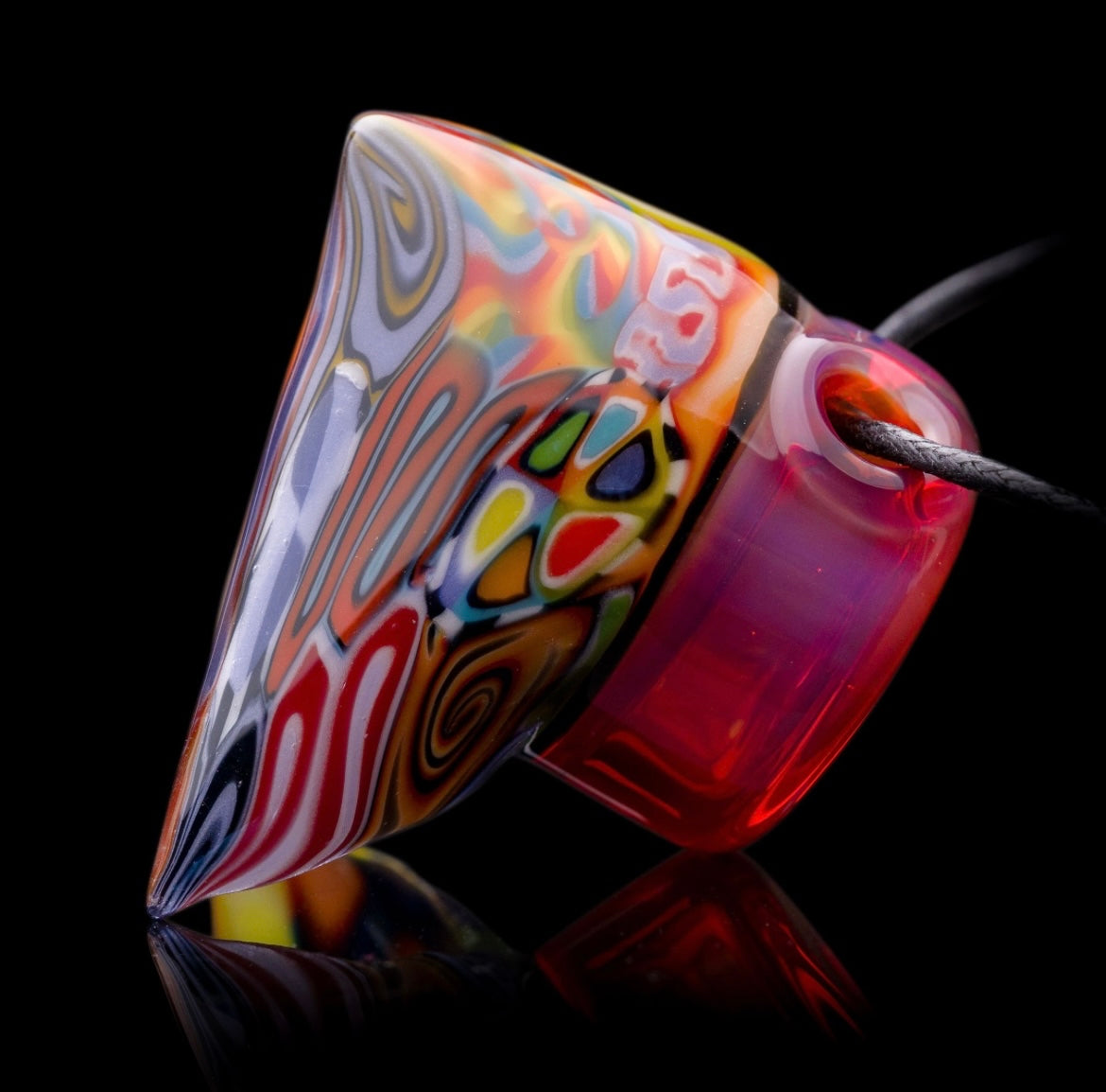 A colorful glass pipe shaped like a reaper with a scythe, featuring abstract designs and a removable dabber.