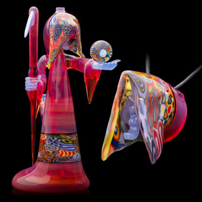 A colorful glass pipe shaped like a reaper with a scythe, featuring abstract designs and a removable dabber.
