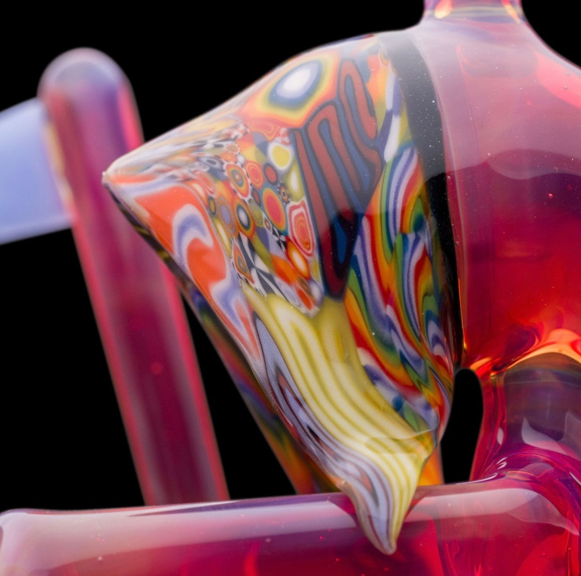 A colorful glass pipe shaped like a reaper with a scythe, featuring abstract designs and a removable dabber.