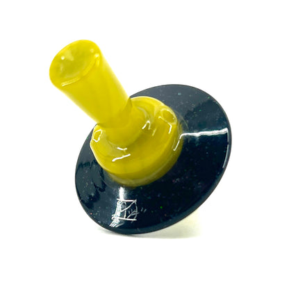 Yellow cap with a dark circular base with white speckles against a white background.